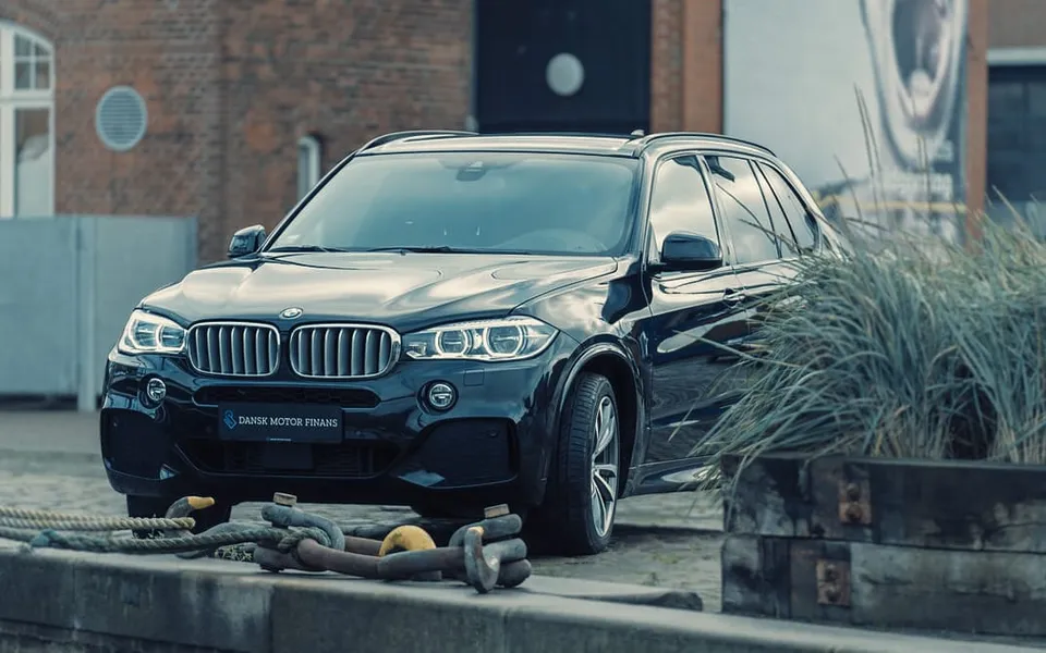 Sort BMW parkeret ved havnen foran en murstensbygning