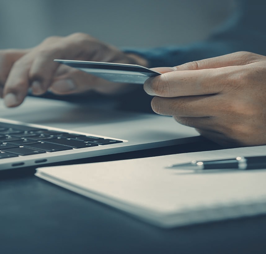 a person holding a card and using a laptop
